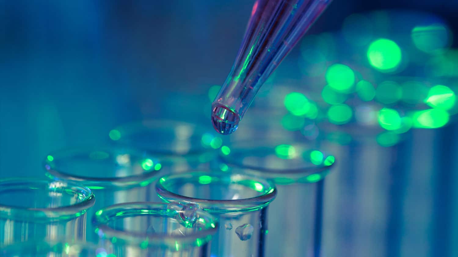 Close-up of sample testing with a dropper adding liquid to test tubes, a biotech use-case that could benefit from a portable cleanroom system